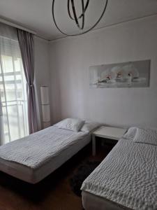 a bedroom with two beds and a chandelier at Orchidea Apartman in Gödöllő