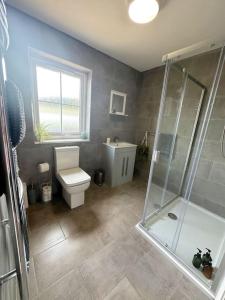 a bathroom with a toilet and a glass shower at Riverside View - Large, modern 4 bedroom house with hot tub in Wooler