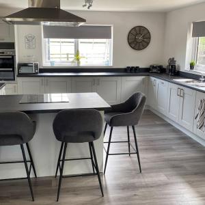 a kitchen with a table and three chairs in it at Riverside View - Large, modern 4 bedroom house with hot tub in Wooler
