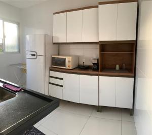La cuisine est équipée de placards blancs et d'un réfrigérateur blanc. dans l'établissement Apartamento Temporada Mobiliado Proximo a Praia, à Vila Velha