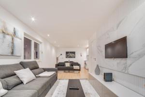 ein Wohnzimmer mit einem Sofa und einem TV an der Wand in der Unterkunft Duplex Apartment near Belém in Lissabon