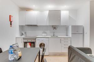 a kitchen with white cabinets and a dog sitting at a table at Duplex Apartment near Belém in Lisbon