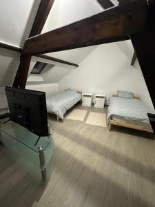 een woonkamer met 2 bedden en een televisie bij BelloHome in La Bretagne