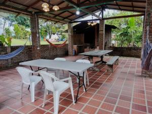 un patio con mesas, sillas y una hamaca en FINCA LA COLONIA en Buga