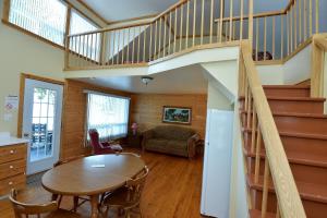 a living room with a table and a staircase at Auberge Sur Mer Charlevoix in Saint-Siméon