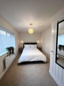 sypialnia z dużym białym łóżkiem i żyrandolem w obiekcie Beautiful 3-Bed House in Bradford w mieście Bradford