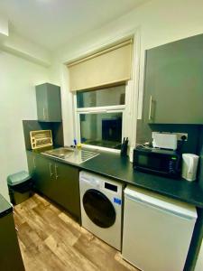 eine Küche mit Waschmaschine, Spüle und Mikrowelle in der Unterkunft Stylish one bed Studio Flat Edgware Road In Central London in London