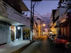 Una calle de la ciudad por la noche con coches aparcados en la calle en Tus Recuerdos, en Santo Domingo
