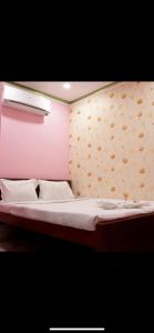 a bed in a room with a pink wall at Hotel Nest Park Street in Kolkata