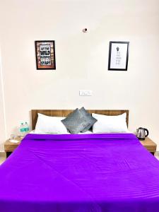 een slaapkamer met een paars bed met twee foto's aan de muur bij Stargaze Inn - Comfy Stays in Greater Noida