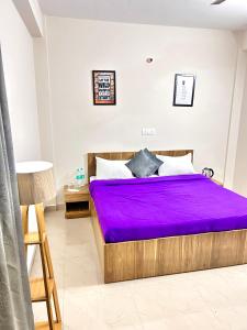 een slaapkamer met een bed met paarse lakens erop bij Stargaze Inn - Comfy Stays in Greater Noida