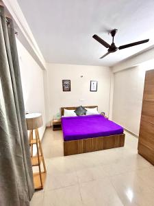 een slaapkamer met een paars bed en een plafondventilator bij Stargaze Inn - Comfy Stays in Greater Noida