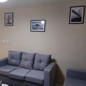 un sofá azul en una sala de estar con fotos en la pared en Acogedor Apartamento en Santiago en Santiago de los Caballeros