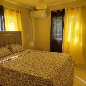 1 dormitorio con 1 cama y una ventana con cortinas amarillas en Acogedor Apartamento en Santiago en Santiago de los Caballeros