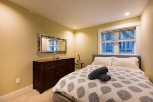 ein Schlafzimmer mit einem Bett mit einem Spiegel und einer Kommode in der Unterkunft Vine & Balsam in Vancouver