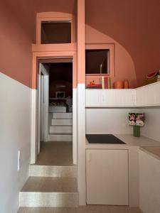 a kitchen with pink walls and white cabinets at IANUA Casa per Viaggiatori in Astypalaia +62 photos