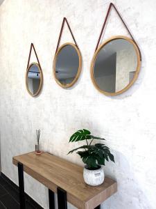 three mirrors on a wall with a table and a plant at Berlen Home apartment in Torre Maggiore