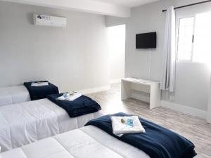 a hotel room with two beds and a television at Pousada TOP in Mairiporã