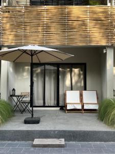un patio con mesa y 2 sillas bajo una sombrilla en Suncloud Hotel Koh Samet en Ko Samed