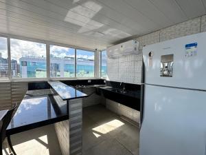 Il comprend une cuisine équipée d'un réfrigérateur et d'une table. dans l'établissement Flat Apartamento, 50m da praia, à João Pessoa