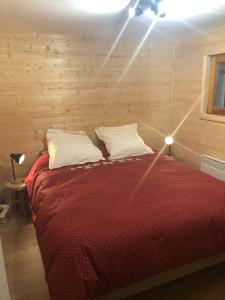 a bedroom with a bed with red sheets and white pillows at Chalet de charme aux Carroz d'Arrâches-Flaines in Les Carroz d'Araches