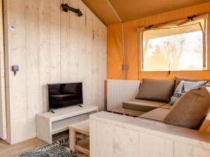 Glamping Lodge في Westerland: غرفة معيشة صغيرة مع أريكة ومدفأة