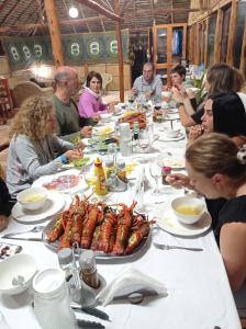 un grupo de personas sentadas alrededor de una mesa comiendo comida en DUNA LODGE en Gudze