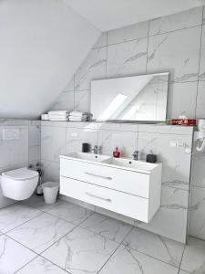 a bathroom with a sink and a toilet and a mirror at Schneider Apartments in Neustadt am Rübenberge +30 photos