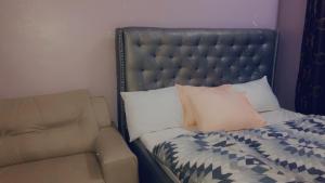 uma cama com um sofá ao lado de uma cama com almofadas em Dazzle Hotels and Apartments Riverpark em Rubuchi