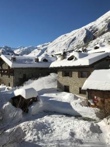 un bâtiment recouvert de neige avec une montagne en arrière-plan dans l'établissement Maison Sarteur Alloggio ad uso turistico -VDA-LA THUILE- 0065, à La Thuile