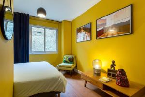 a bedroom with yellow walls and a bed and a chair at Stella - 2 chambres-balcon- place de la République in Lyon