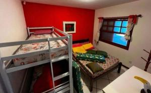 Ce lit se trouve dans un dortoir doté de 2 lits superposés et d'un mur rouge. dans l'établissement Chácara Campo Verde, à Bragança Paulista
