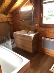 een badkamer met een bad, een wastafel en een spiegel bij Chalet de charme aux Carroz d'Arrâches-Flaines in Les Carroz d'Araches