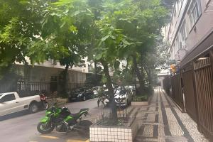 a motorcycle parked next to a tree on a street at Apto Luxuoso, 50 Mts da Praia em Copacabana para 6 in Rio de Janeiro