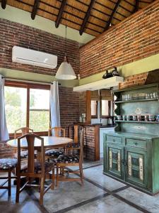 a kitchen with a table and chairs and a brick wall at Hermoso quincho a pasos del mar in Playa Verde