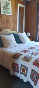 Una cama grande con una manta de ganchillo. en CABAÑA HUALAIHUE AUSTRAL, en Hornopirén