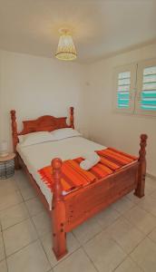 a bedroom with a wooden bed with white sheets at LES KOKI VILLA MOJITO in Saint-François
