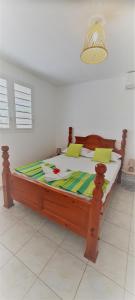 1 dormitorio con cama de madera en una habitación en LES KOKI VILLA MOJITO en Saint-François