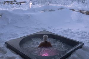 a person in a hot tub in the snow at Tupasvilla in Saariselka
