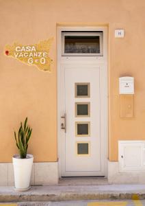 una porta bianca con un cartello su un edificio di Casa Vacanze GeO a Mazara del Vallo