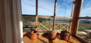 普圖的住宿－Cabañas Rahue Lafquen，一组铜盆坐在窗前的桌子上