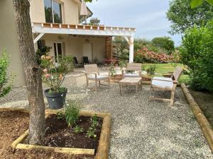 a patio with chairs and a table and a tree at Logement entier de charme, gite équestre GERS Flamarens in Flamarens