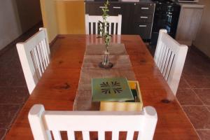 una mesa de madera con sillas blancas y un jarrón en la parte superior en Kuyay Cabañas, en San Rafael 11 fotos más