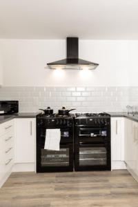 um fogão preto numa cozinha com armários brancos em Suite 4 - Trendy Spot in Oldham City Centre em Oldham