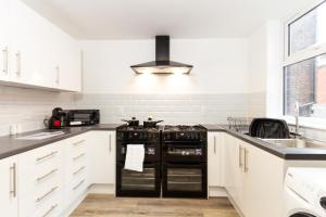 une cuisine avec des armoires blanches et des appareils noirs dans l'établissement Suite 4 - Trendy Spot in Oldham City Centre, à Oldham