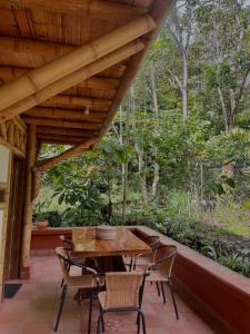 een houten tafel en stoelen op een veranda met bomen bij Oasis Santuario de Naturaleza in Ibagué