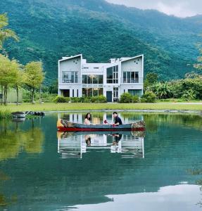 Shuhuにある靜樹湖民宿Jing Shuhu B&Bの家の前の水中のカヌーに乗った二人