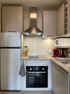 a kitchen with a white refrigerator and a stove at Appartement Cosy Proche du Lac in Annecy