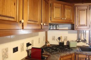 a kitchen with wooden cabinets and a stove top oven at Maison Sarteur Alloggio ad uso turistico -VDA-LA THUILE- 0065 in La Thuile