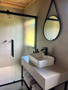 ein Badezimmer mit einem weißen Waschbecken und einem Spiegel in der Unterkunft Chalé Caminhos do Salto Ventoso in Farroupilha